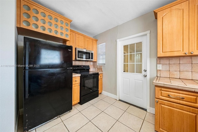 4625 SW 32nd Dr, West Park, FL 33023 - kitchen featuring black appliances, decorative backsplash, light tile patterned floors, tile counters, and light brown cabinets