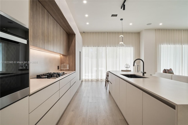 18955 Atlantic Blvd, Sunny Isles Beach, FL 33160 - kitchen featuring modern cabinets, gas cooktop, light countertops, a center island with sink, and light wood-type flooring