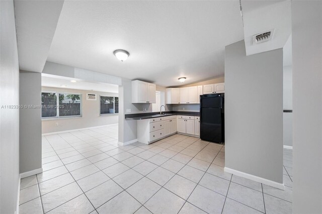 3818 Everglades Rd, Palm Beach Gardens, FL 33410 - kitchen with freestanding refrigerator, dark countertops, light tile patterned floors, white cabinetry, and lofted ceiling