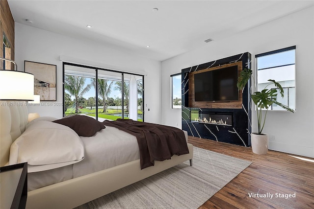 9741 SE Gomez Ave, Hobe Sound, FL 33455 - bedroom featuring access to outside, wood finished floors, a glass covered fireplace, and recessed lighting