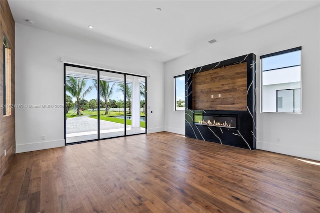 9741 SE Gomez Ave, Hobe Sound, FL 33455 - unfurnished living room featuring hardwood / wood-style floors, a glass covered fireplace, and recessed lighting