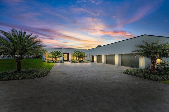 9741 SE Gomez Ave, Hobe Sound, FL 33455 - modern home with stucco siding, community garages, driveway, and a lawn