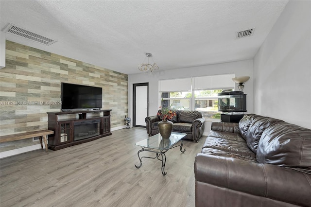 5576 SW 7th St, Margate, FL 33068 - living room with a textured ceiling, wood finished floors, an accent wall, and a glass covered fireplace