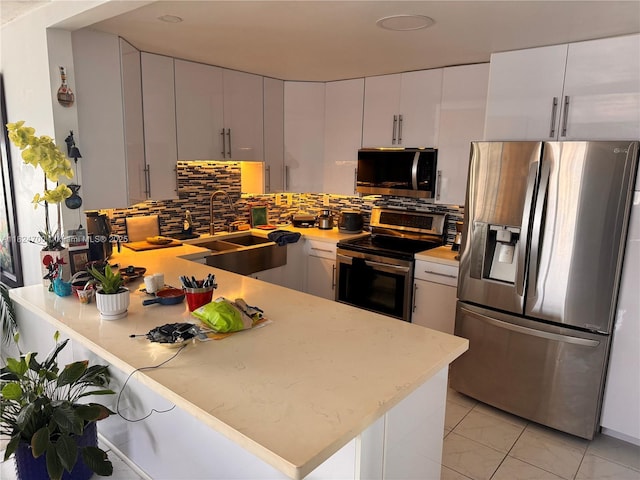 2750 NE 183rd St Unit 2103, Aventura, FL 33160 - kitchen with appliances with stainless steel finishes, a peninsula, tasteful backsplash, light marble finish floors, and white cabinetry