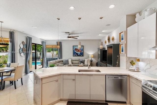 1273 SW 161st Ave, Pembroke Pines, FL 33027 - kitchen featuring appliances with stainless steel finishes, open floor plan, a peninsula, decorative backsplash, and light stone countertops