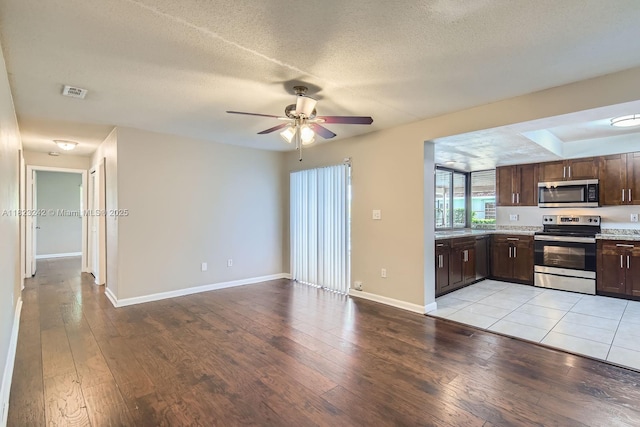 1708 NW 84th Dr, Coral Springs, FL 33071 - kitchen featuring appliances with stainless steel finishes, light wood-type flooring, dark brown cabinetry, ceiling fan, and a textured ceiling