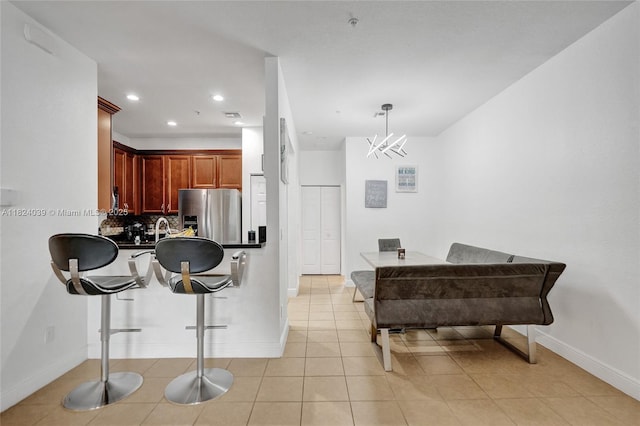 11854 SW 27th St, Miramar, FL 33025 - kitchen with stainless steel fridge, a breakfast bar area, tasteful backsplash, reddish brown cabinets, and dark countertops