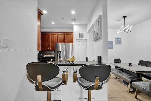 11854 SW 27th St, Miramar, FL 33025 - kitchen with stainless steel fridge with ice dispenser, a breakfast bar area, tasteful backsplash, light tile patterned flooring, and a chandelier