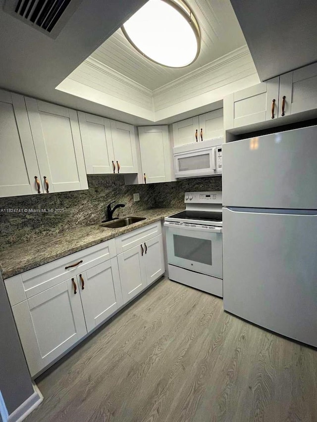 3515 Van Buren St Unit 106, Hollywood, FL 33021 - kitchen with white appliances, a tray ceiling, light wood-style floors, ornamental molding, and backsplash