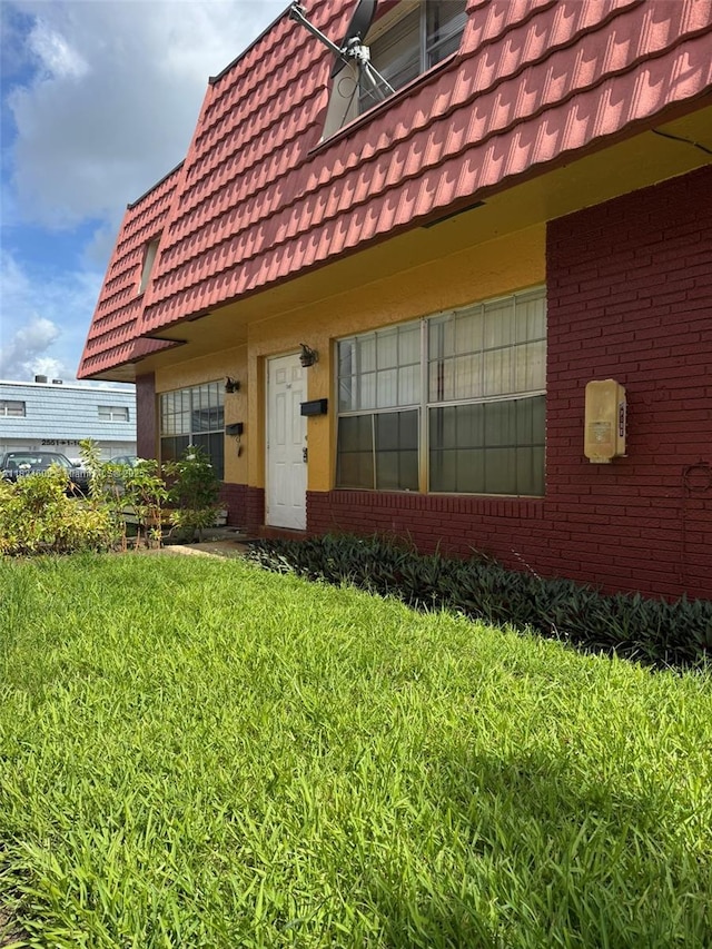 2562 NW 52nd Ave Unit B18, Lauderhill, FL 33313 - property entrance featuring a tiled roof, a yard, brick siding, and mansard roof