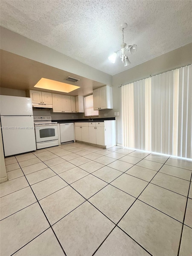 2562 NW 52nd Ave Unit B18, Lauderhill, FL 33313 - kitchen with white appliances, dark countertops, light tile patterned floors, under cabinet range hood, and a textured ceiling