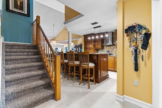 10091 SW 137th Pl, Miami, FL 33186 - indoor bar with wall chimney range hood, stairway, hanging light fixtures, ornate columns, and tasteful backsplash