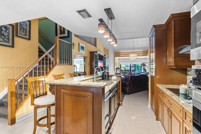 10091 SW 137th Pl, Miami, FL 33186 - kitchen with open floor plan, black electric stovetop, light stone countertops, an island with sink, and decorative light fixtures