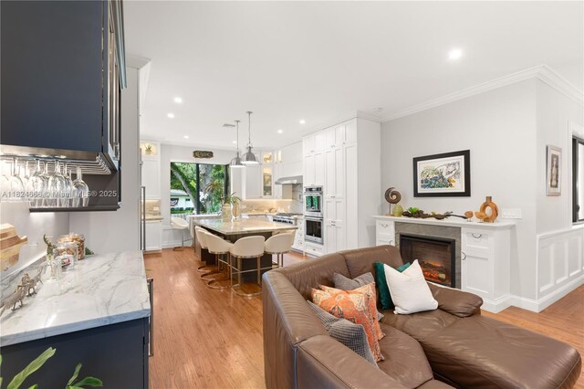 1460 Mantua Ave, Coral Gables, FL 33146 - living room with light wood-type flooring, a warm lit fireplace, ornamental molding, and recessed lighting