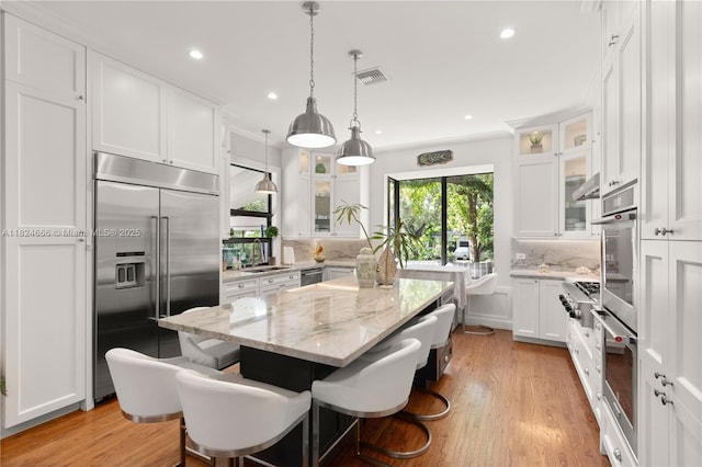 1460 Mantua Ave, Coral Gables, FL 33146 - kitchen featuring stainless steel appliances, a kitchen island, white cabinets, decorative backsplash, and light stone countertops