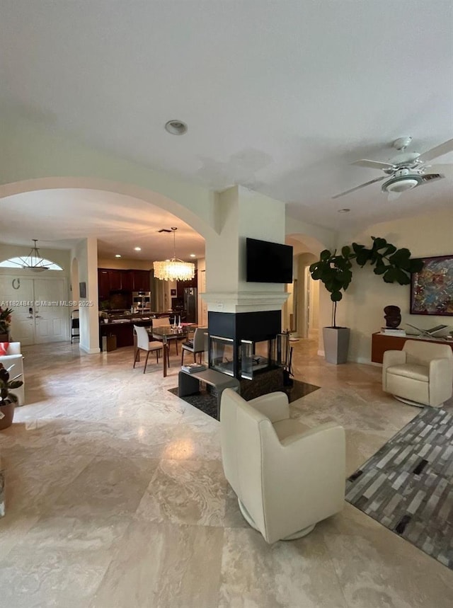 810 NE 21st Dr, Wilton Manors, FL 33305 - living area featuring arched walkways, a ceiling fan, a chandelier, a multi sided fireplace, and recessed lighting