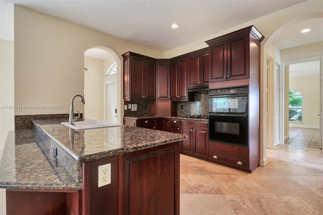 810 NE 21st Dr, Wilton Manors, FL 33305 - kitchen with arched walkways, dark brown cabinets, tasteful backsplash, dark stone counters, and recessed lighting