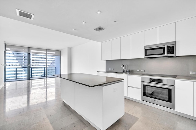 88 SW 7th St Unit 1006, Miami, FL 33130 - kitchen featuring appliances with stainless steel finishes, modern cabinets, a kitchen island, white cabinets, and expansive windows