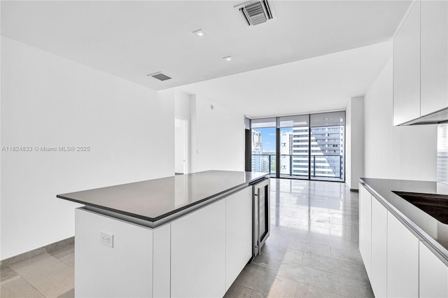 88 SW 7th St Unit 1006, Miami, FL 33130 - kitchen with a wall of windows, dark countertops, white cabinetry, a kitchen island, and modern cabinets