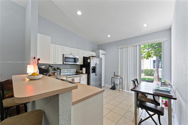 18739 SW 28th St, Miramar, FL 33029 - kitchen with appliances with stainless steel finishes, light countertops, white cabinetry, light tile patterned flooring, and lofted ceiling