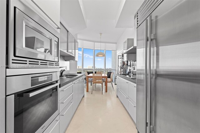18201 Collins Ave Unit 201A, Sunny Isles Beach, FL 33160 - kitchen featuring built in appliances, modern cabinets, dark countertops, white cabinets, and a wall of windows