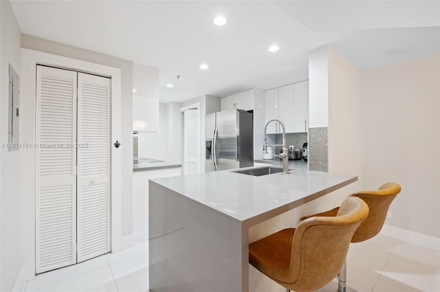 701 Brickell Key Blvd Unit 1605, Miami, FL 33131 - kitchen with stainless steel fridge, modern cabinets, white cabinets, decorative backsplash, and a peninsula