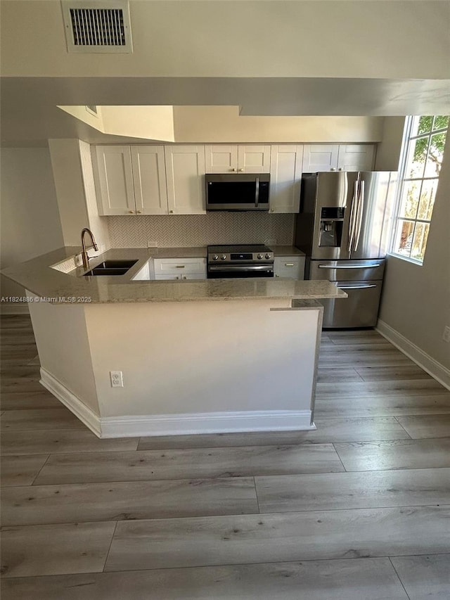 2921 NE 185th St Unit 1205, Aventura, FL 33180 - kitchen featuring appliances with stainless steel finishes, a peninsula, white cabinets, and wood finished floors