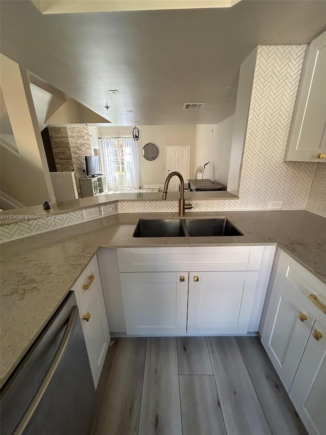 2921 NE 185th St Unit 1205, Aventura, FL 33180 - kitchen with stainless steel dishwasher, white cabinetry, tasteful backsplash, light stone countertops, and wood finished floors