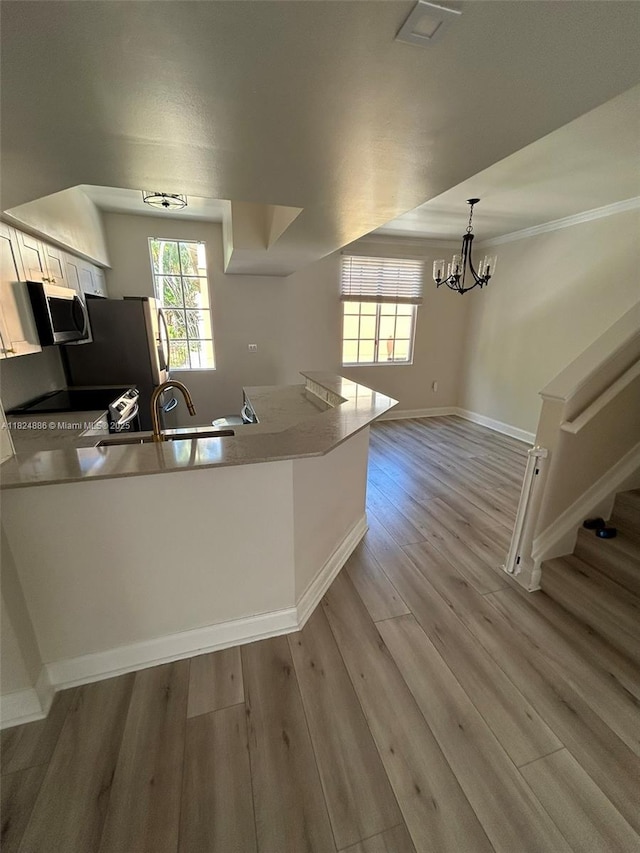 2921 NE 185th St Unit 1205, Aventura, FL 33180 - kitchen featuring a peninsula, light wood-type flooring, a chandelier, appliances with stainless steel finishes, and white cabinetry