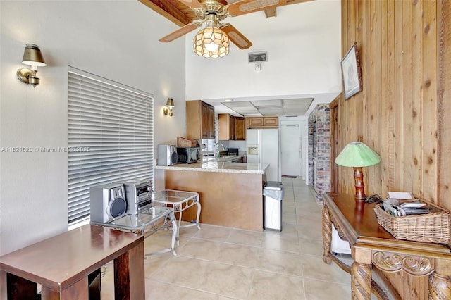 1600 SW 72nd Ave, Plantation, FL 33317 - kitchen featuring white refrigerator with ice dispenser, light tile patterned floors, ceiling fan, wooden walls, and brown cabinets
