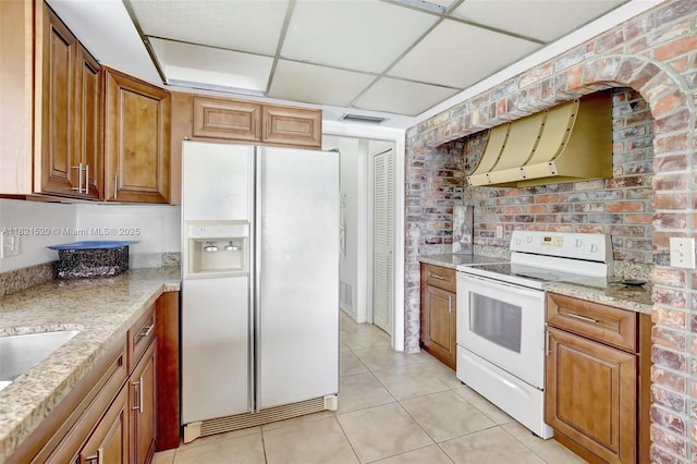 1600 SW 72nd Ave, Plantation, FL 33317 - kitchen featuring white appliances, premium range hood, light tile patterned flooring, brown cabinetry, and light stone counters