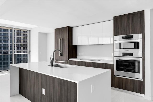 488 NE 18th St Unit 4112, Miami, FL 33132 - kitchen with modern cabinets, double oven, light countertops, dark brown cabinetry, and a center island with sink