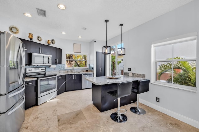 20709 NW 1st St, Pembroke Pines, FL 33029 - kitchen with appliances with stainless steel finishes, a peninsula, a breakfast bar area, hanging light fixtures, and dark cabinets
