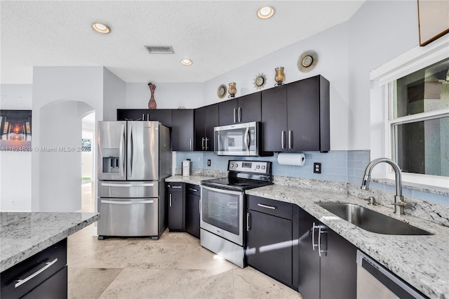 20709 NW 1st St, Pembroke Pines, FL 33029 - kitchen with appliances with stainless steel finishes, light stone counters, backsplash, arched walkways, and a textured ceiling