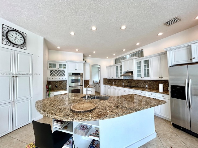 5058 SW 170th Ave, Miramar, FL 33027 - kitchen with stainless steel appliances, arched walkways, light tile patterned floors, open shelves, and a textured ceiling