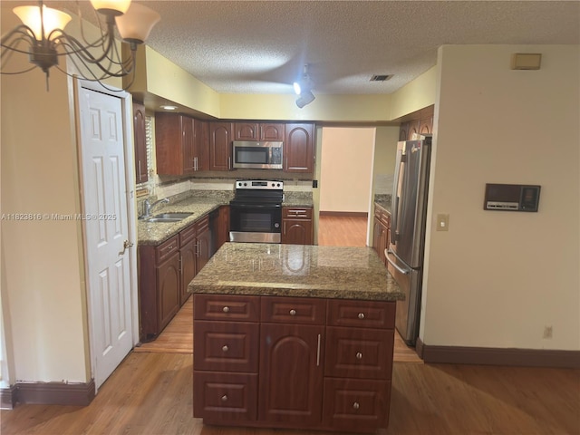 2660 Huron Way, Miramar, FL 33025 - kitchen with appliances with stainless steel finishes, light wood finished floors, a kitchen island, a chandelier, and a textured ceiling
