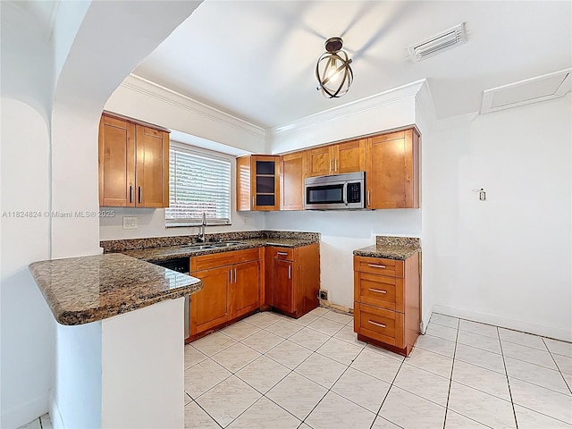 6464 Mcclellan St, Hollywood, FL 33024 - kitchen featuring stainless steel microwave, brown cabinets, a peninsula, dark stone countertops, and ornamental molding