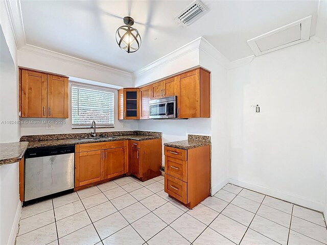 6464 Mcclellan St, Hollywood, FL 33024 - kitchen featuring appliances with stainless steel finishes, brown cabinetry, ornamental molding, and dark stone counters