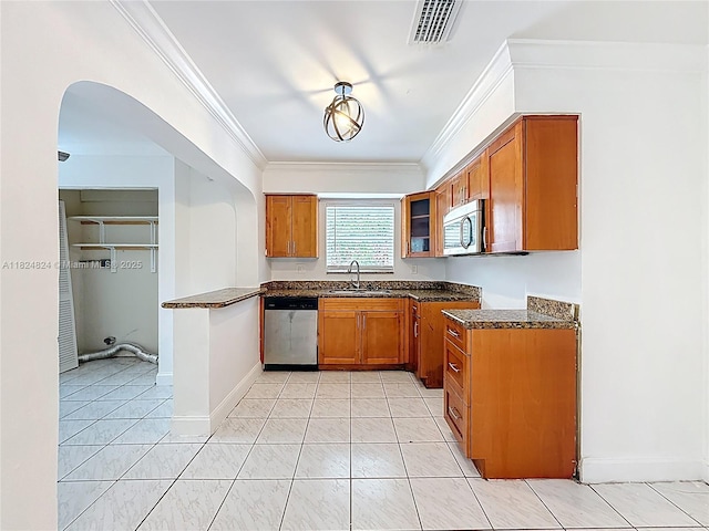 6464 Mcclellan St, Hollywood, FL 33024 - kitchen featuring appliances with stainless steel finishes, brown cabinetry, ornamental molding, arched walkways, and dark stone countertops