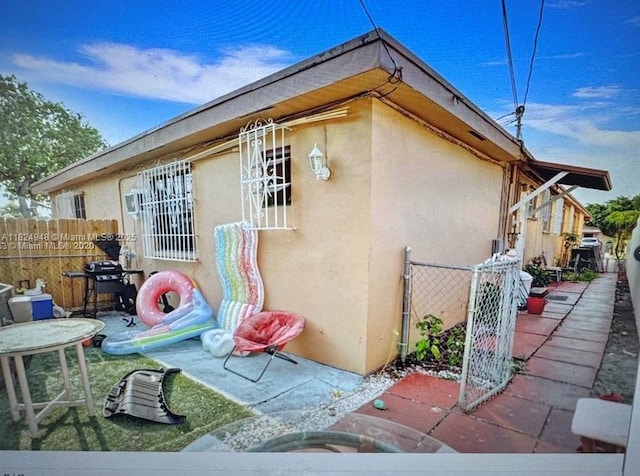 166 E 16th St, Hialeah, FL 33010 - view of property exterior with stucco siding, a gate, and a patio