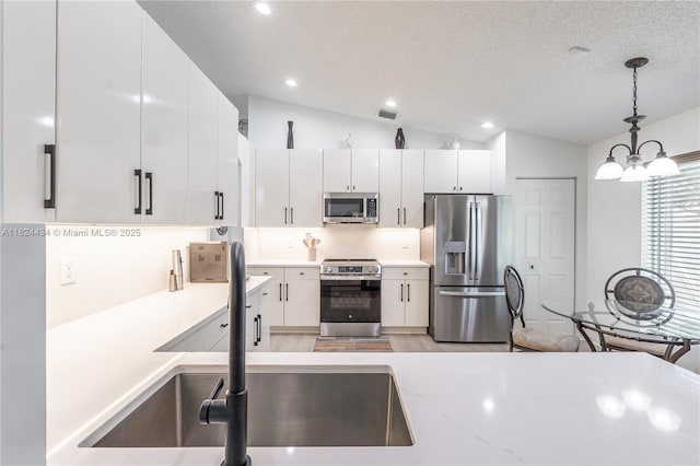 14295 NW 18th Pl, Pembroke Pines, FL 33028 - kitchen with stainless steel appliances, lofted ceiling, decorative light fixtures, white cabinetry, and a chandelier
