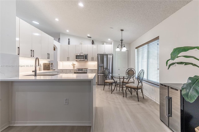 14295 NW 18th Pl, Pembroke Pines, FL 33028 - kitchen featuring stainless steel appliances, a textured ceiling, light wood-style flooring, vaulted ceiling, and a peninsula