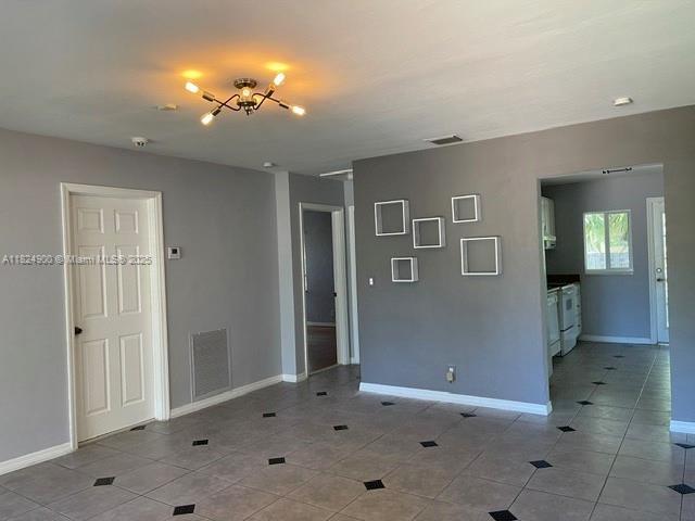 5433 NE 5th Ave, Oakland Park, FL 33334 - empty room with light tile patterned floors, a smoke detector, and a chandelier
