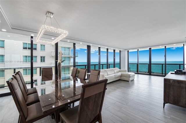 9455 Collins Ave Unit 809, Surfside, FL 33154 - dining space with floor to ceiling windows, a chandelier, a water view, and wood finished floors