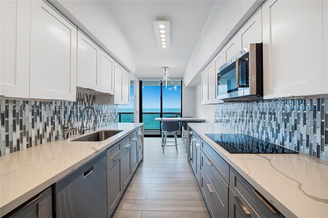 9455 Collins Ave Unit 809, Surfside, FL 33154 - kitchen with stainless steel appliances, tasteful backsplash, light wood-style floors, white cabinetry, and light stone countertops