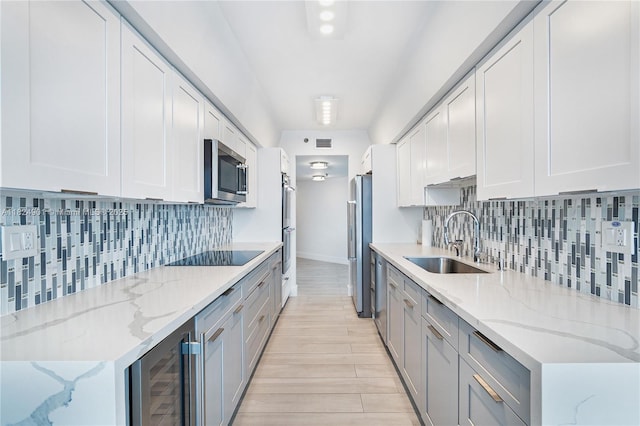 9455 Collins Ave Unit 809, Surfside, FL 33154 - kitchen with appliances with stainless steel finishes, wine cooler, decorative backsplash, light wood-style floors, and white cabinetry