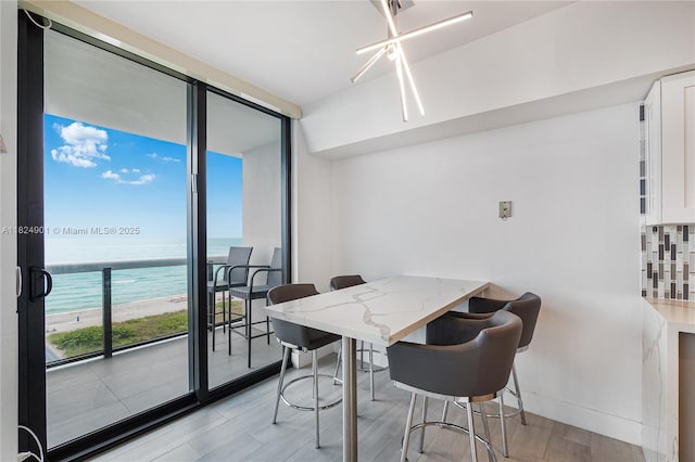 9455 Collins Ave Unit 809, Surfside, FL 33154 - dining space with a water view, a wall of windows, and light wood finished floors