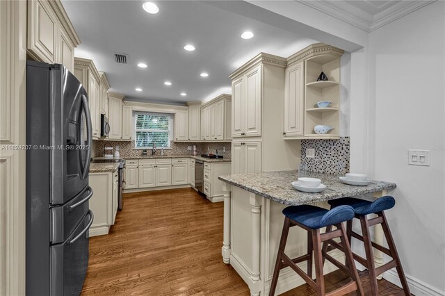 433 NE 91st St, Miami Shores, FL 33138 - kitchen featuring stainless steel appliances, crown molding, wood finished floors, light stone counters, and recessed lighting