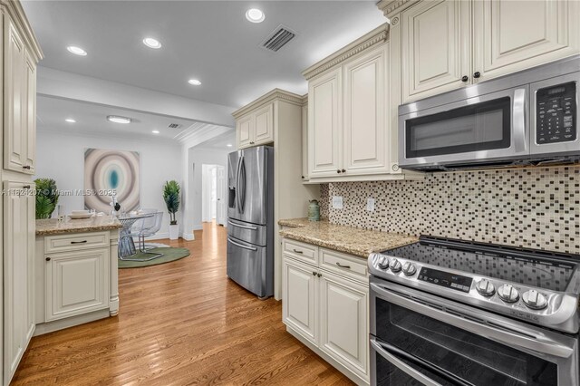 433 NE 91st St, Miami Shores, FL 33138 - kitchen featuring stainless steel appliances, light wood-style floors, tasteful backsplash, recessed lighting, and light stone counters