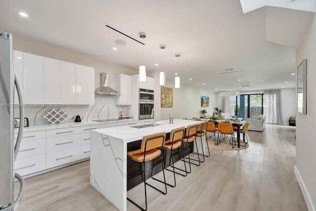 1101 NE 16th Ter Unit 1, Fort Lauderdale, FL 33304 - kitchen featuring wall chimney range hood, modern cabinets, stainless steel appliances, light wood finished floors, and white cabinets